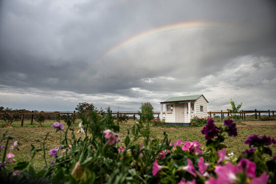 Grey sky and Small rainbow above a tiny white house 