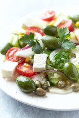 Healthy Salad with Feta Cheese, Green Olives, Baby Spinach, Cucumber, Cherry Tomatoes and Capers. Bright background. Close up.	