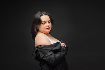 A woman in a black jacket wears a white bra. The concept of confidence and empowerment as a woman proudly shows off her bra. A black jacket adds sophistication. Fat woman.