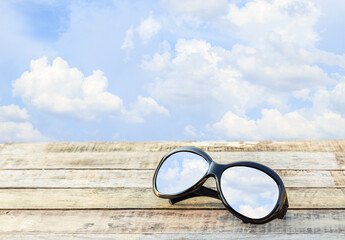 Clear sky in eyeglasses on the wooden background