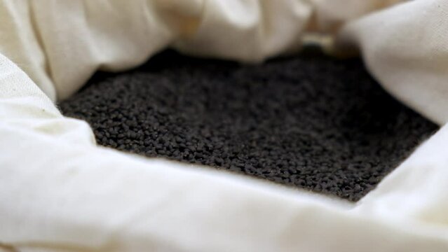 Pullback shallow depth shot of black basil seeds in bag