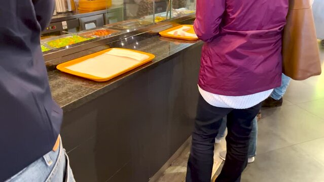 People queuing to collect their lunch from a diner. Static view