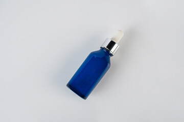 Blue glass cosmetic bottle on white background.