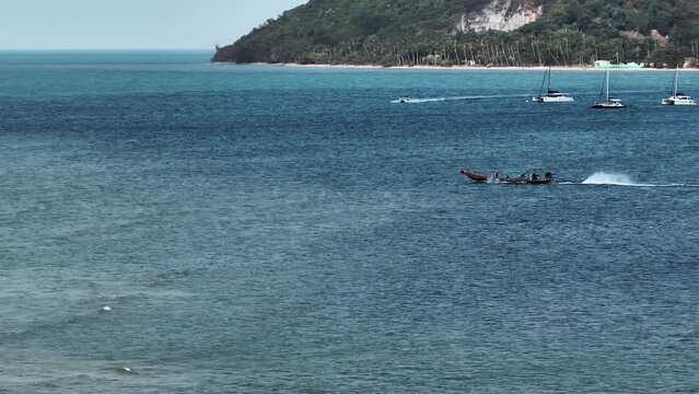 Wide tracking shot of single boat departing to sea from Thai coastline. Fast ship riding out to ocean from shore, Thailand.