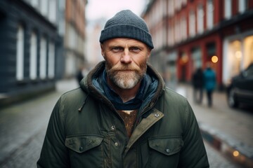 Portrait of a bearded man with a gray beard in a green jacket on a city street