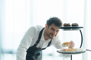 A young man puts on an apron to make dessert to eat with his wife. Checking the completeness of the finished dessert.