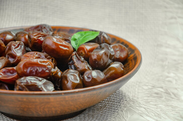 Dates in a brown plate on a textured light background, side view