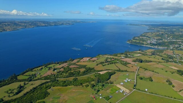 Aerial view over farmlands, toward Fish farms on the coast of Lemuy island, Chiloe