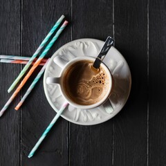 Cup of espresso coffee served with rock candy sticks over dark wooden background