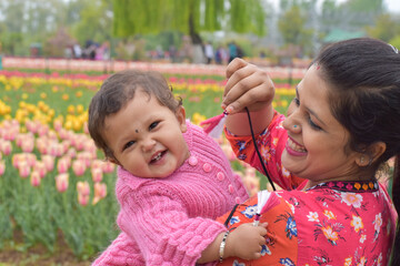 Mother and healthy baby posing in Tulip Garden Kashmir . selective focus on subject and background...