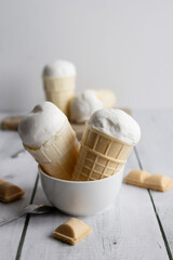 Vanilla ice cream in waffle cones on a white wooden background. dessert