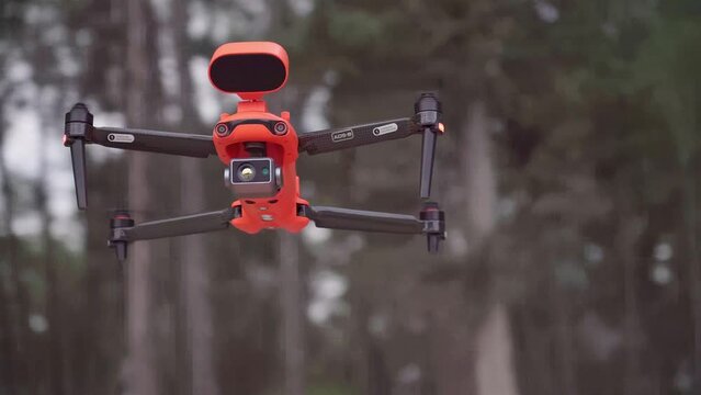 Drone flying in mid air. orbital shot of a drone flying in mid air with trees in the background. Drone quadcopter with camera flying. Smart farming agriculture tech or military drone flying around