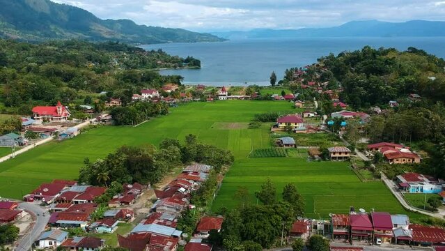 Stunning aerial of Lake Toba with village, mountains, and blue water in Sumatra, Indonesia.