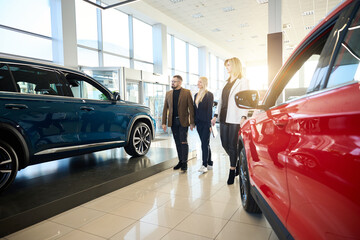 People walk along new cars for sale