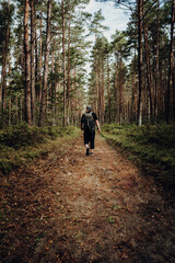 A hiker with a backpack runs along a path through the forest