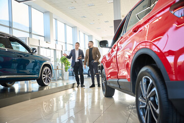 Salesman showing new cars to man buyer
