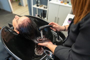 Hairdresser rinsing shampoo from a woman's hair at the salon