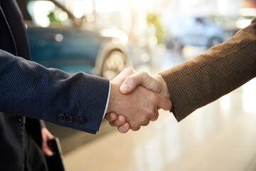 Two people shaking hands in a car dealership