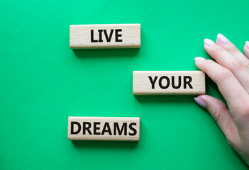 Live your Dreams symbol. Wooden blocks with words Live your Dreams. Beautiful green background....