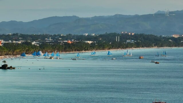 White beaches with turquoise sea water and paraw sailing boats. Dusk time in Boracay, Philippines.