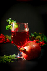 ripe pomegranate and glass of wine on Red background. Background has Flowers