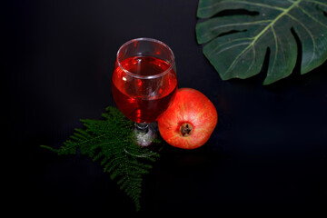 ripe pomegranate and glass of wine on black background. Closup