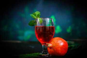 ripe pomegranate and glass of wine on Red background. Background has Flowers