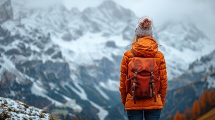 A person with a backpack stands on a mountain peak