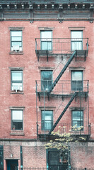 Old red brick building with fire escapes, color toning applied, New York City, USA.