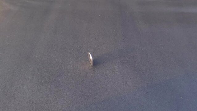 A Two Rupees Indian Coin Spinning On Black Paper in Slow Motion, spinning and tipped over