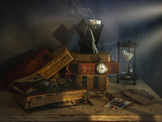 Still life with old things. The extinguished candle is still smoking. A stack of tattered books....