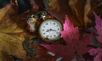 Pocket watch with a chain against the background of old, tattered books. Vintage.