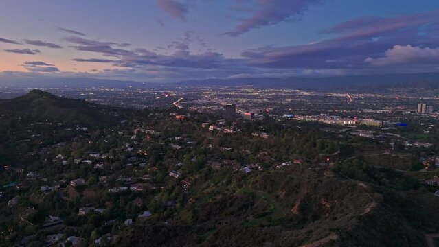 Aerial panorama of homes in Hollywood Hills at dusk, San Fernando Valley cityscape in the background. Los Angeles, California.