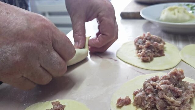 woman hands making homemade dumplings at the kitchen table.
