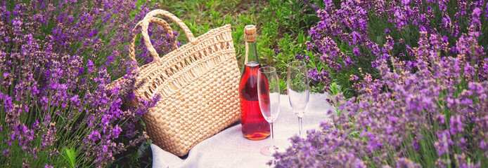 two glasses and pink wine in a lavender field. Violet flowers on the background