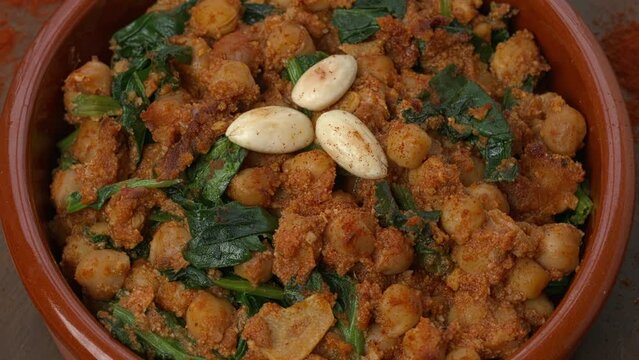 Closeup view of homemade Spinach and Chickpeas (Espinacas con Garbanzos) with smoked paprika seasoning scattered on a table. Table spin.