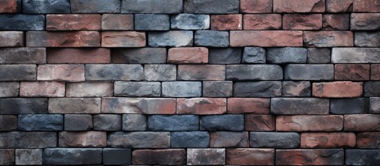 Obraz premium A brick wall constructed using bricks of various colors, presenting a unique and abstract texture. The bricks are cemented together to form a sturdy and visually striking barrier.