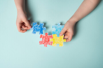Children's hands laying out a colored puzzle, symbol of World Autism Awareness Day.