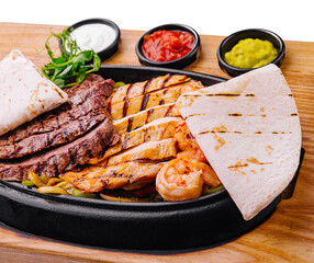 Beef chicken and shrimp fajitas on a iron cast sizzling plate