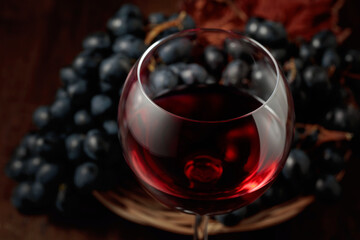 Red wine and blue grapes on an old wooden table.
