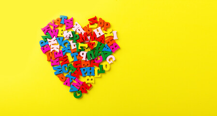 colored letters of the alphabet in the shape of a heart on a yellow background