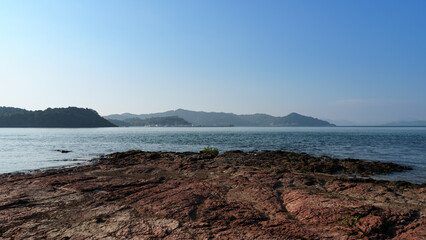 Fototapeta na wymiar Coastal rocks and distant harbor