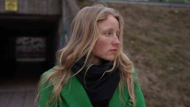 Adult woman portrait outside. Natural female without make-up with long blond hair. Serious woman face outside. Cold weather, female wears coat.