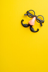 Get into the April Fool's spirit: Vertical top view of comical eyewear with a faux mustache and nose, showcased on a bright yellow canvas, with space for your personalized text or ad - obrazy, fototapety, plakaty