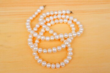 Pearl necklace on wooden background.