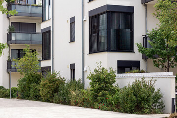 Fototapeta na wymiar Modern Facade Building with Landscape Design front House. Modern White Exterior Design of Multifamily Low rise Apartment Building with Courtyard Garden Landscaping.