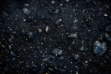 A close-up of asphalt road with a dark gray color and some white speckles. The background is black and there is a slight vignette - obrazy, fototapety, plakaty