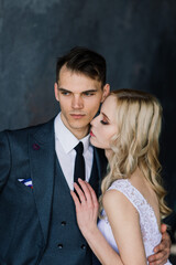 Cute wedding couple in the interior of a classic studio decorated. They kiss and hug each other.