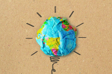 Light bulb drawing and planet earth on crumpled recycled paper - Concept of ecology and green energy innovation