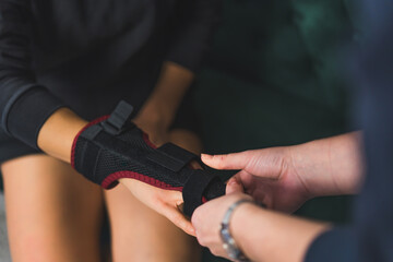closeup shot of a person helping a woman in adjusting two-sided splint on the middle finger. High quality photo - obrazy, fototapety, plakaty